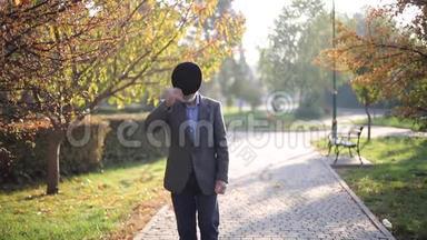 英俊的老人穿上灰色夹克和黑色帽子。 白发苍苍的胡须<strong>老头</strong>走在秋天的公园里.. 黄色